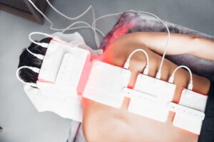 Several white LED therapy pads with cables placed across a client's upper back