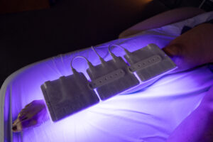 Row of LED therapy pads glowing violet-blue during a light therapy session