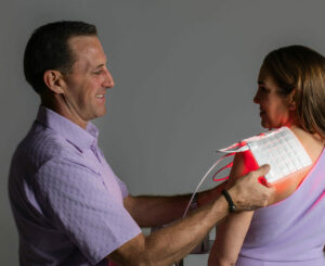 Jeff McKeever demonstrating a LightMD red light therapy pad during a live photobiomodulation demo at UltraRed