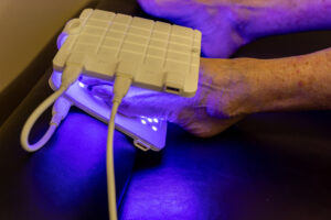 Client's foot resting on an LED pad emitting blue and violet light