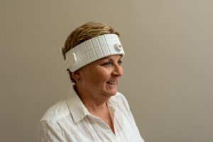 Smiling older woman wearing a white LED headband for brain-focused light therapy