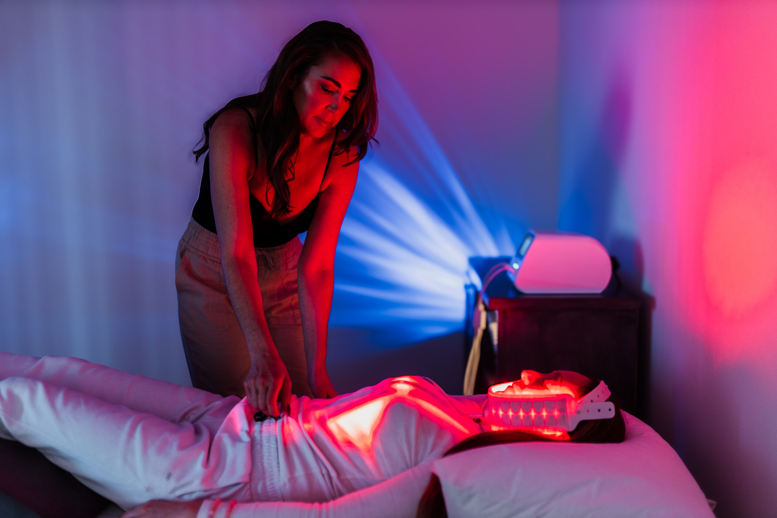 Brooke McKeever placing red light therapy pads on a client during a personalized PBM session at UltraRed Light Therapy in Newport Beach